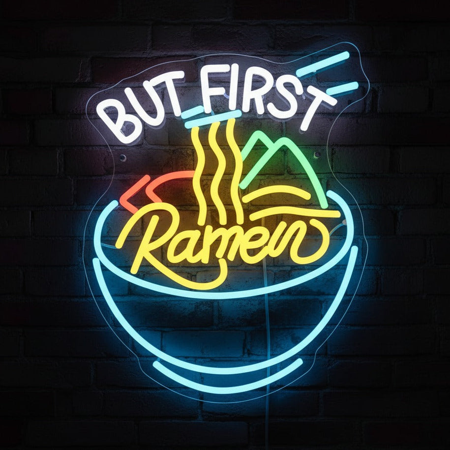 Neon sign with 'But First, Ramen' text on a brick wall background