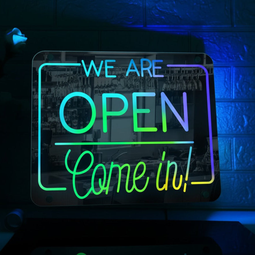 Neon sign with 'We are open, come in!' text on a dark background