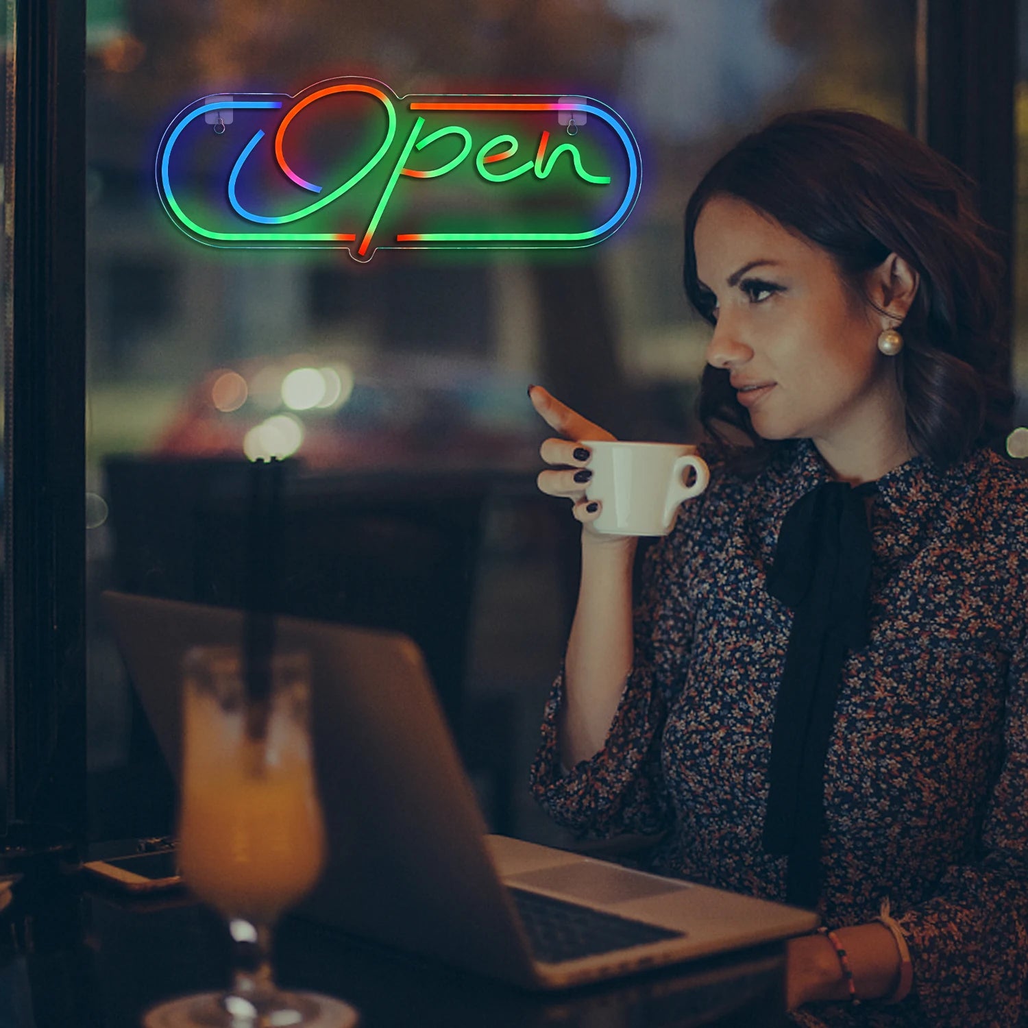 Woman sitting at a cafe with a neon 'Open' sign in the background