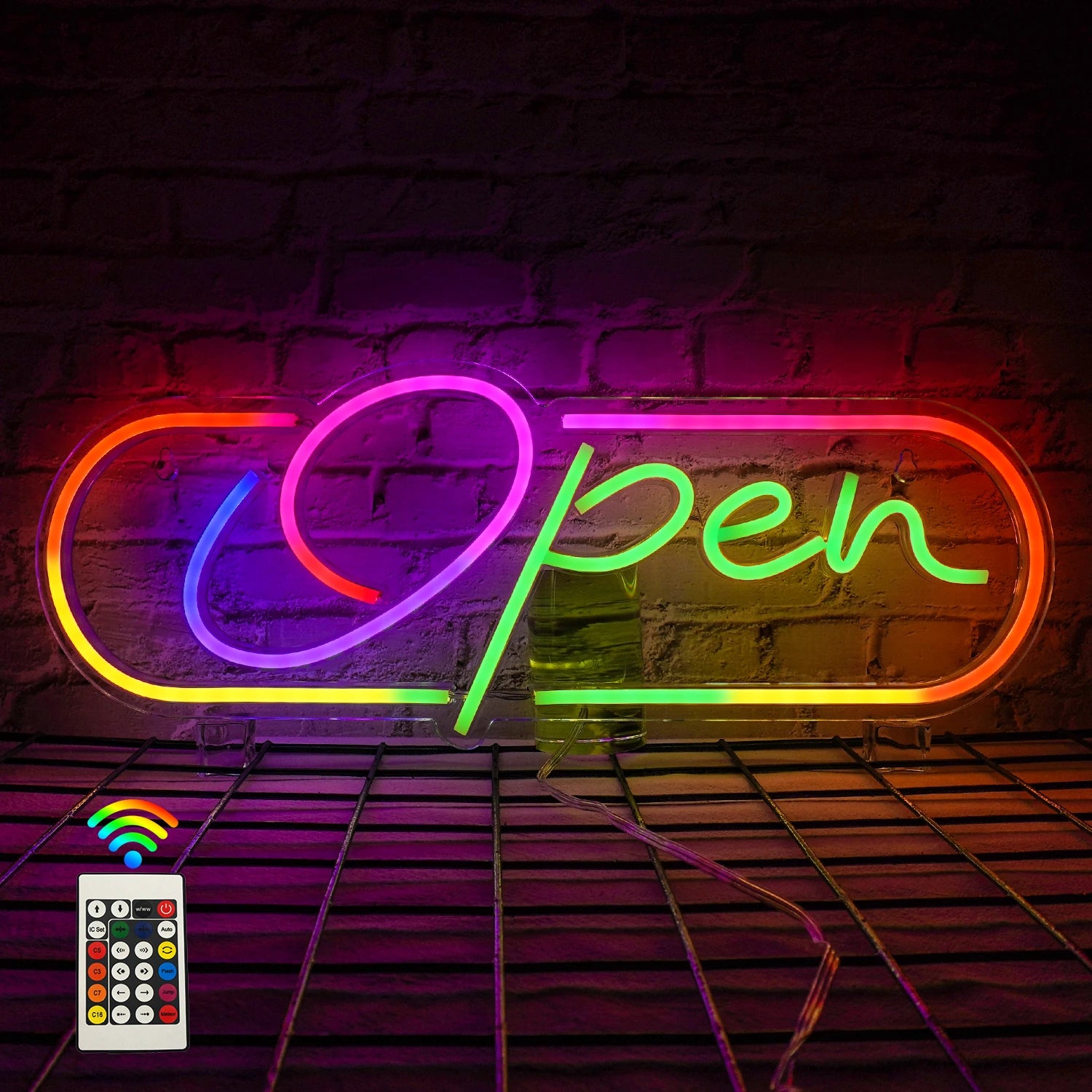 Neon sign with 'Open' text on a brick wall background, featuring a remote control.