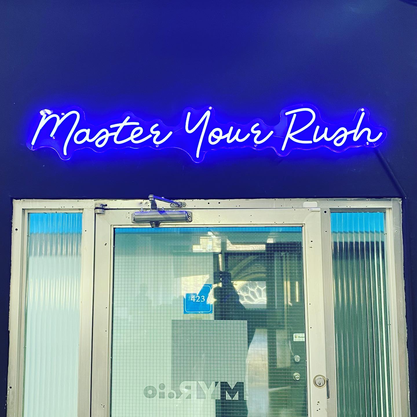 blue neon sign that says "master your rush"
